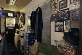 Naraのbar アット ザ ディープの内観写真です。壁には色々な写真が飾られています。ハンガーには洋服が掛けられます。入り口横にはダーツの機械が置かれていて、ダーツを楽しむことができます。