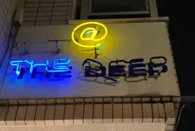 奈良市 新大宮駅から徒歩約7分の所に位置するbar @ the deepのネオンの看板です。@のもじが黄色theの文字が青く光っています。