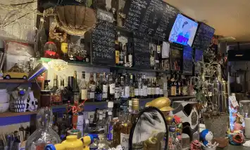 奈良市の新大宮にあるBar「@ the deep」の内観写真でカウンターの写真。黒板には白のチョークでメニューが書かれています。棚にはたくさんのお酒が並んでいます。