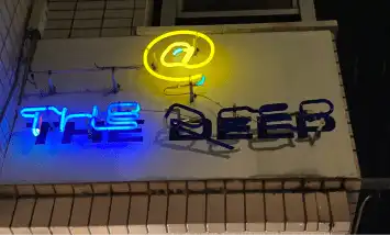 奈良市 新大宮駅から徒歩約7分の所に位置するbar @ the deepのネオンの看板です。@のもじが黄色theの文字が青く光っています。