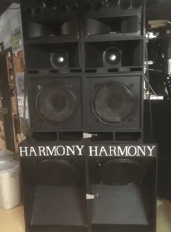 正面に黒色のHARMONY SOUNDSYSTEMが置かれている。lowboxには白色でHARMONYと書かれている。 屋内イベント会場の写真